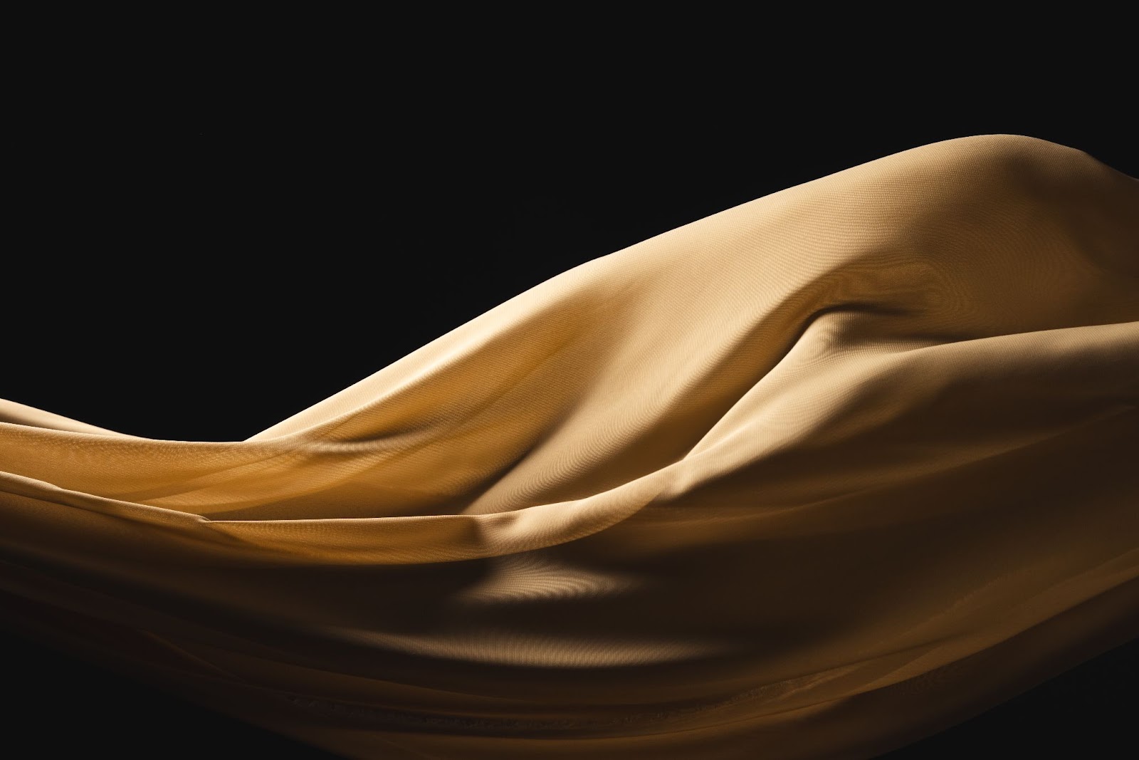 Silk flowing in front of a black wall