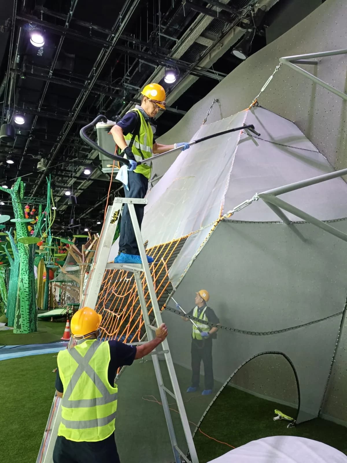 A Crusade technician working at height from a ladder on an exhibition build