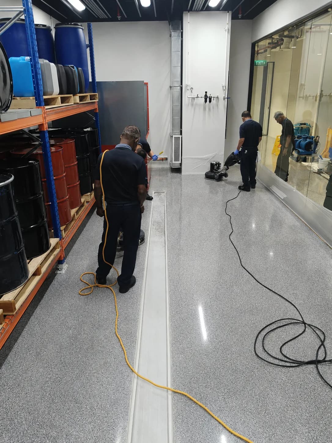 Crusade technicians machine-cleaning a warehouse corridor floor