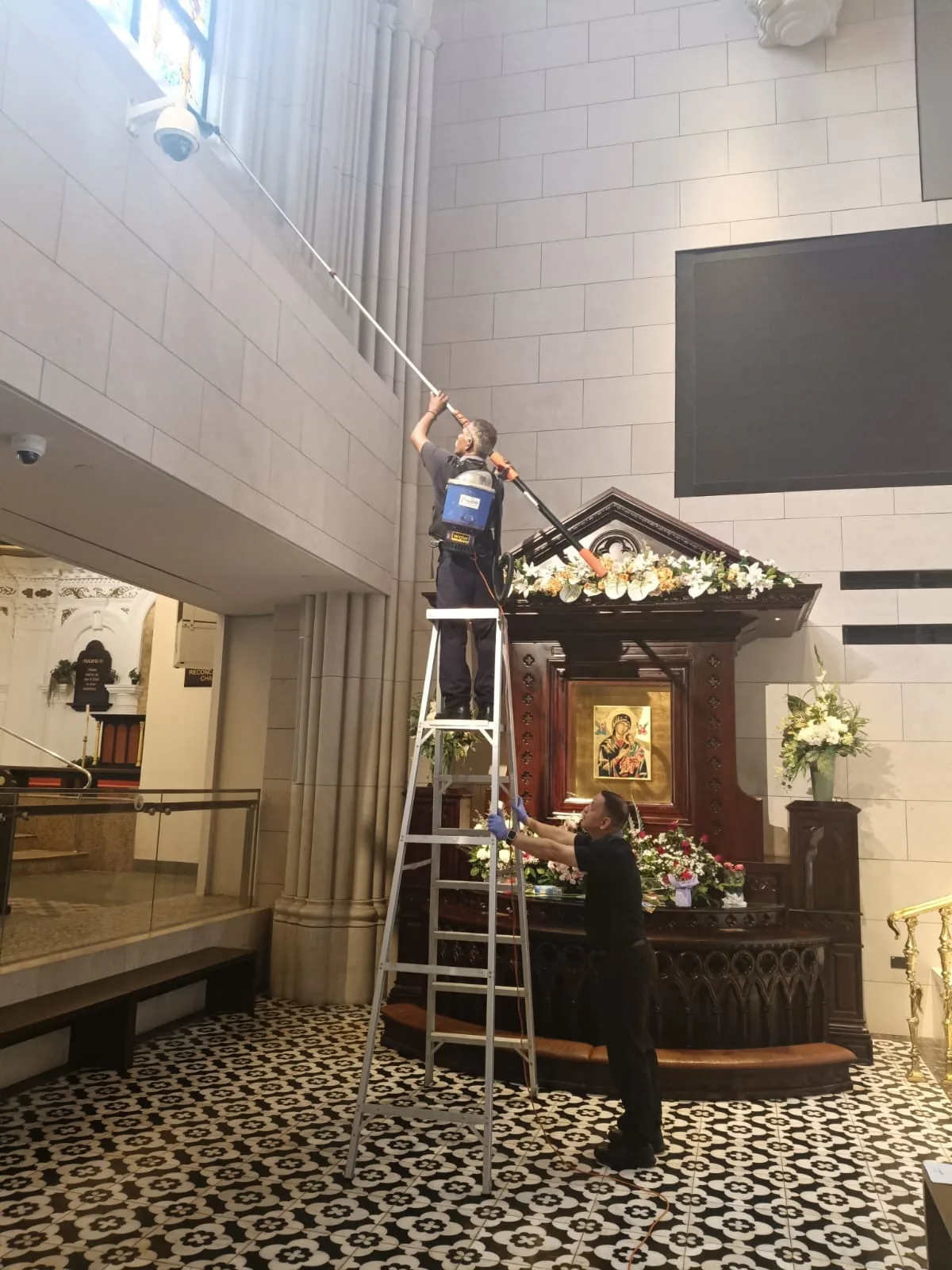 A Crusade technician cleaning an atrium at height from a ladder