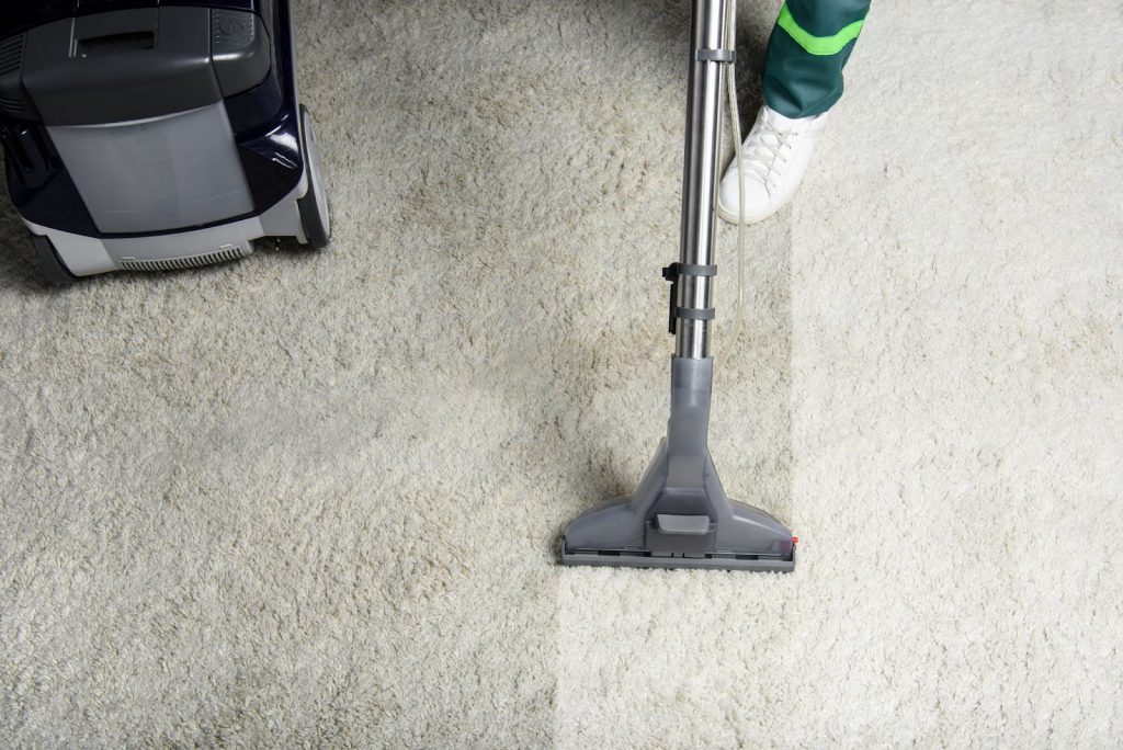 a person vacuuming a dirty rug to clean it.