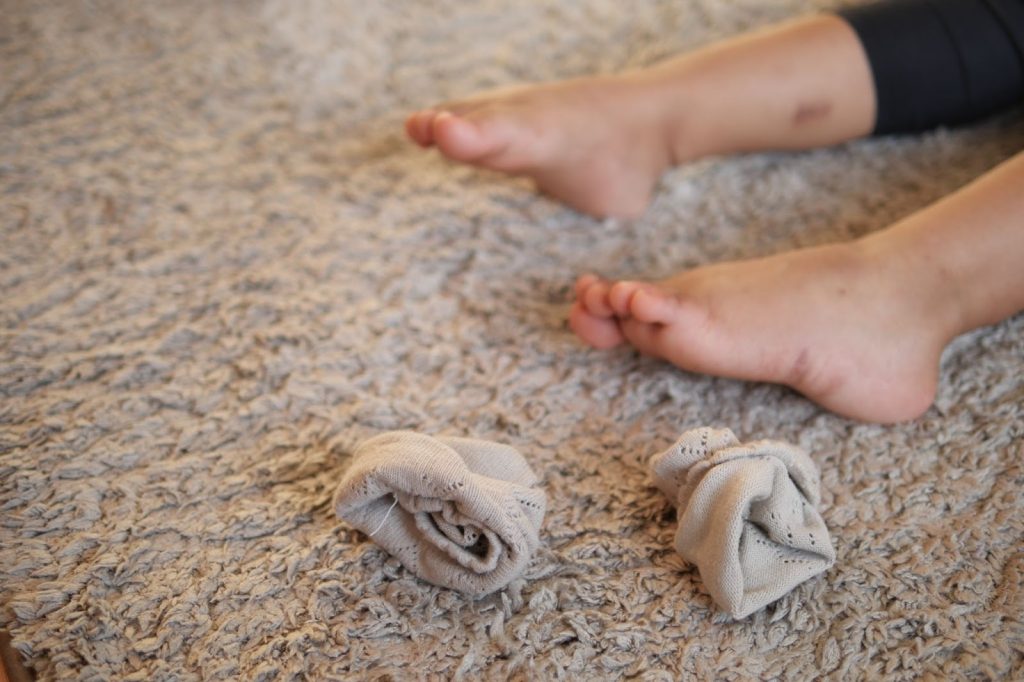 bare feet on a shaggy rug with two rolled up socks