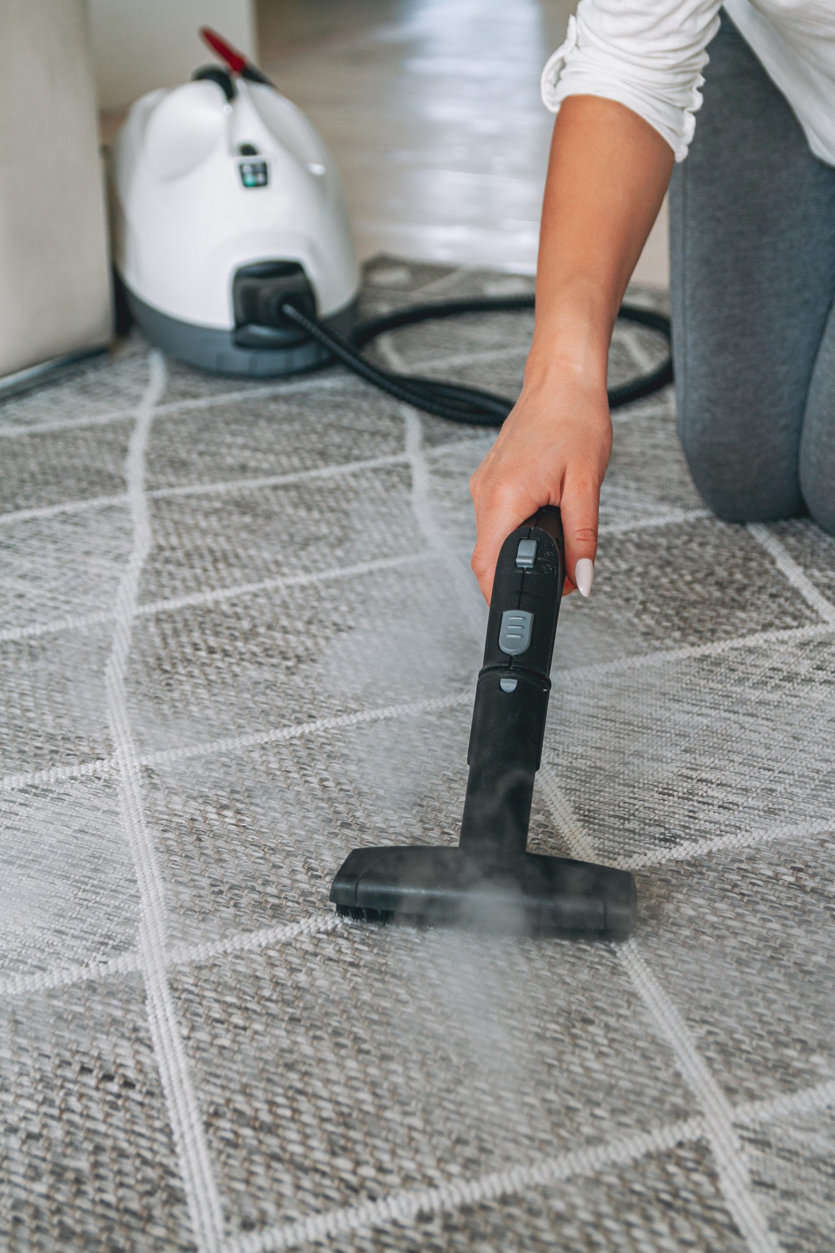 Woman cleaning carpet with steam cleaner